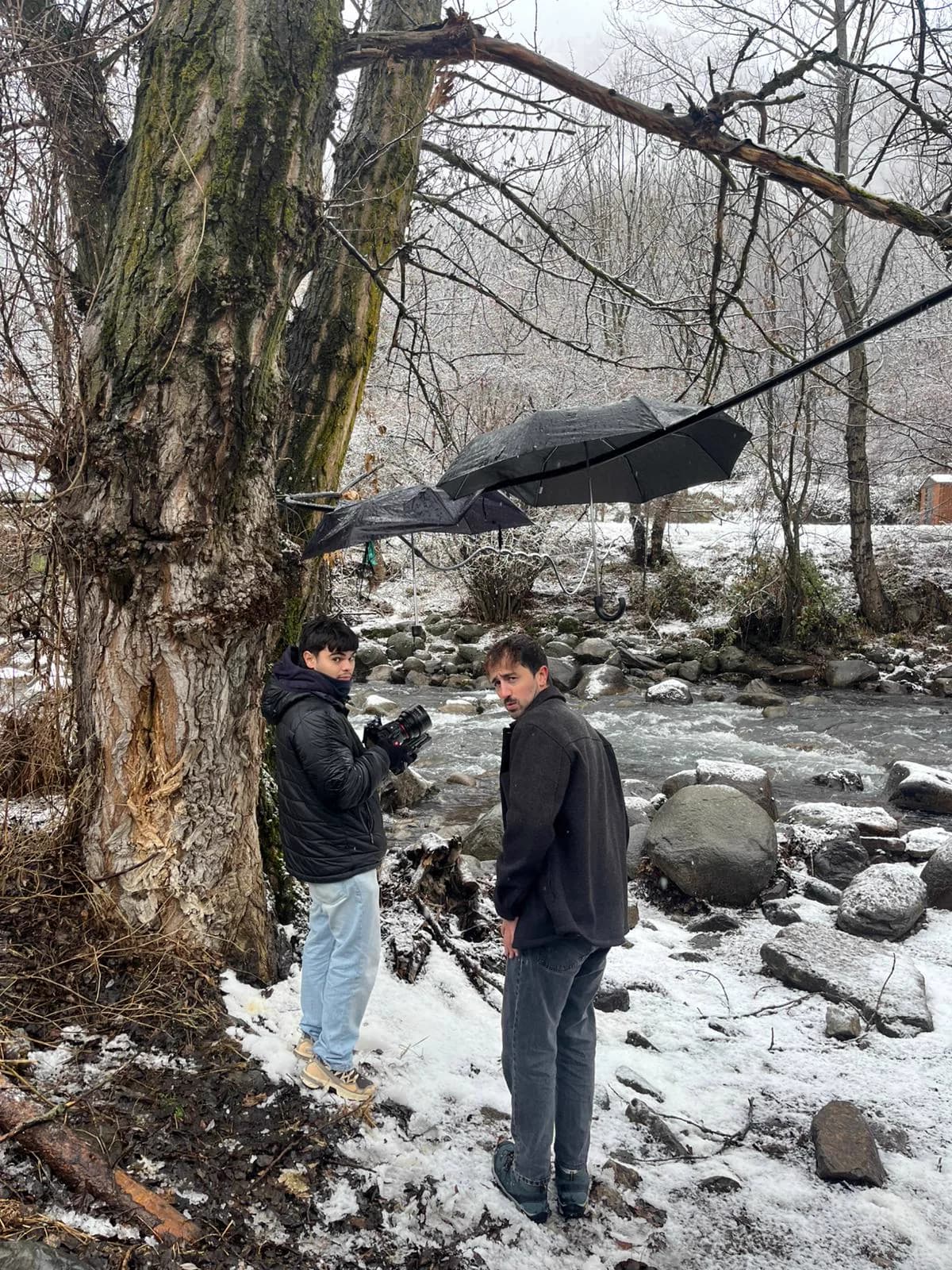 Dos membres de l'equip preparant una càmera al costat d'un riu nevat