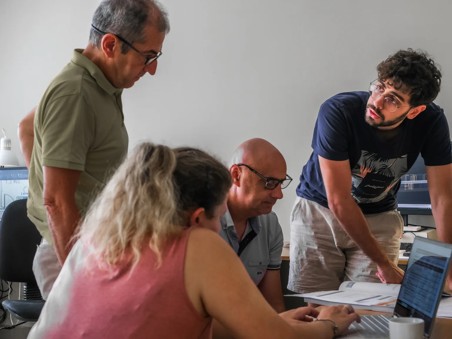 Equip professional col·laborant al voltant d'una taula de treball